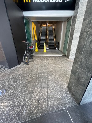 Path to entrance from street. Doors ahead. Pillar on right.