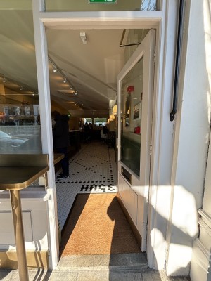 Glass door with white frames. Push on left to open.