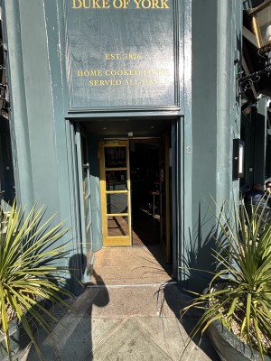 From pavement facing venue. Planters on left and right. Entrance doors at the back.