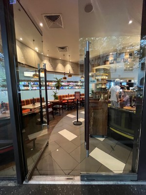 Glass door with black metal handles in middle. Push to open.
