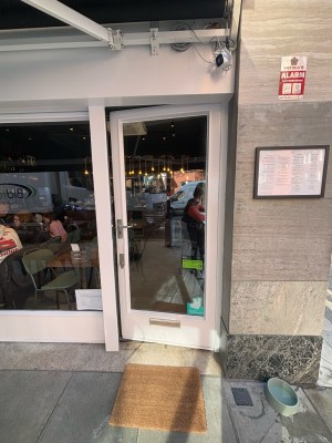 Glass door with white wooden frame ahead. Push metal handle at left to open.