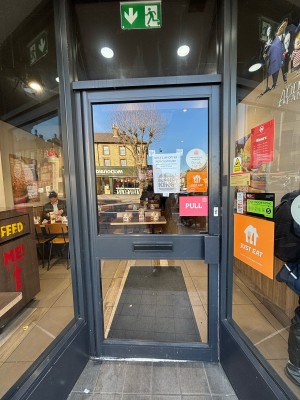 Glass door with black frames. Pull handle on right to open.