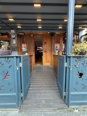 From pavement facing venue. Blue half doors ahead. Push in centre to open.