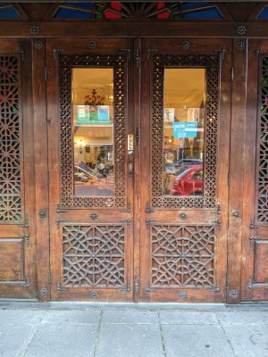 Glass and wood doors with metal handle in centre. Pull to open.