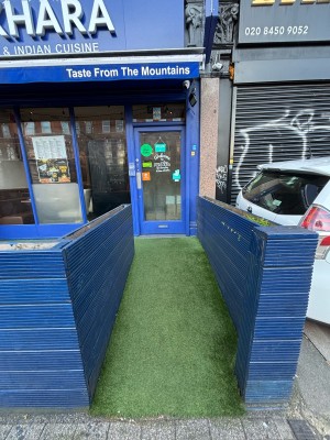 From pavement facing straight. Built in ramp slopes up to door at the back. Fence on left and right.