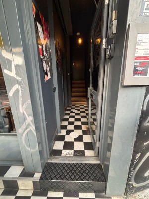 One step up to glass door with grey frames. Push on left to open.