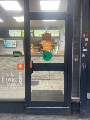 Glass door with black frame ahead. Push from left to open.