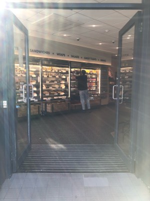 Glass doors with grey frame. Push handles in centre to open.