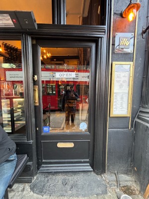 Glass door with black frames. Push gold handle on left to open.
