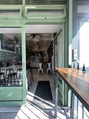 Glass door ahead with green metal frame. Push silver handle on left to open.