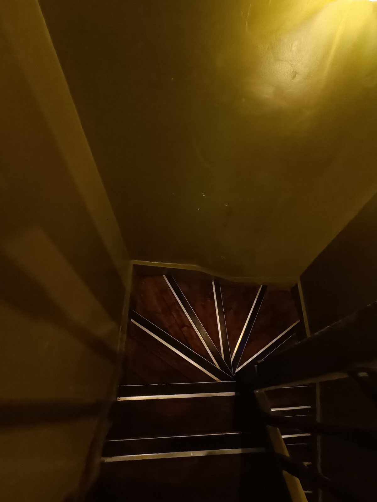 From end of handrail, looking straight. Stairs ahead curving to right.