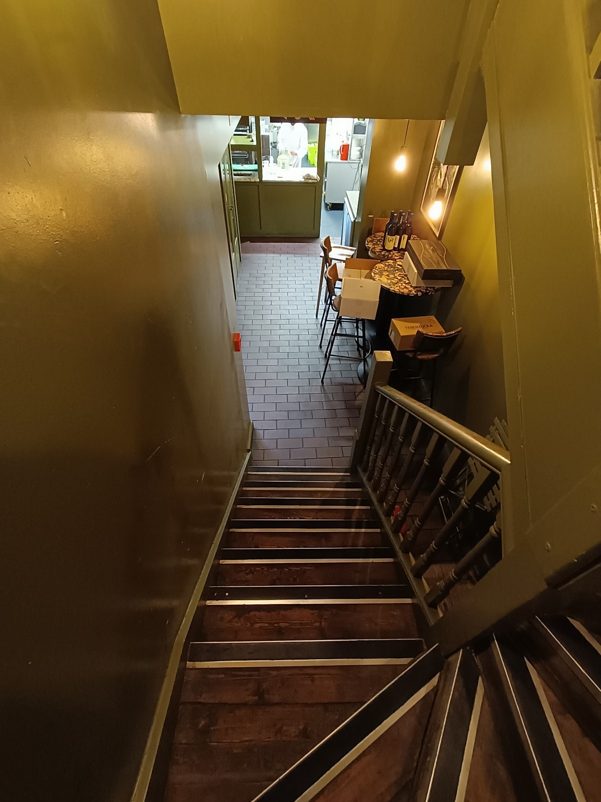 From curve of stairs, looking right. Stairs ahead. Grey, wooden handrail along right.