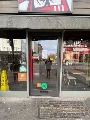 Metal-framed glass door. Push from red metal handle on left to open.