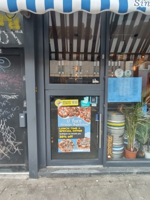 Grey framed glass door. Push silver handle at bottom right to open.