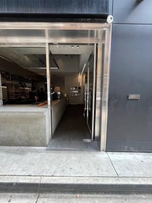 Glass door with silver metal frame and silver handle on left. Push to open.