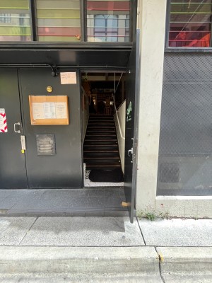Black wooden door with silver handle on left. Pull to open. Door typically kept open.