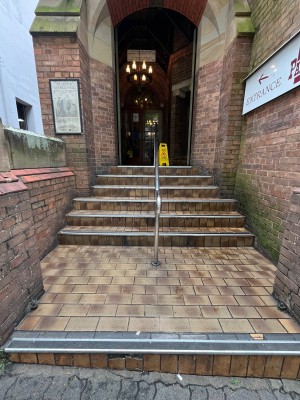 Steps to entrance. One step up to staircase. Handrail dividing staircase in middle.