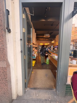 Glass door with grey frame ahead. Push at center right to open.