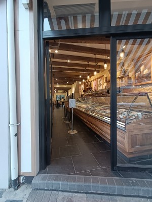 Glass door with black, metal frame. Push black handle on right to open.