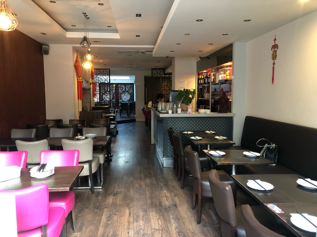 From entrance facing right. Tables with chairs along left wall. Half booth along right, counter behind.