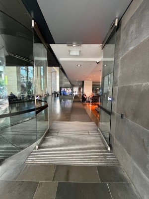 From right of revolving doors facing straight. Glass double doors open outwards from middle.