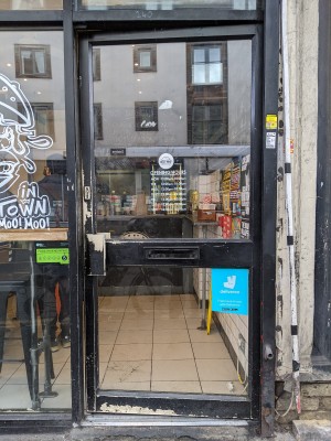 Glass door with black frame and black handle on left. Push to open.