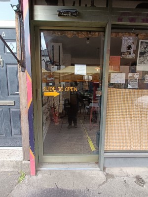 Glass door with green metal frame. Slide green metal handle from left to right to open.