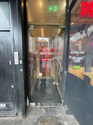 Glass door ahead. Push silver metal handle on right to open.