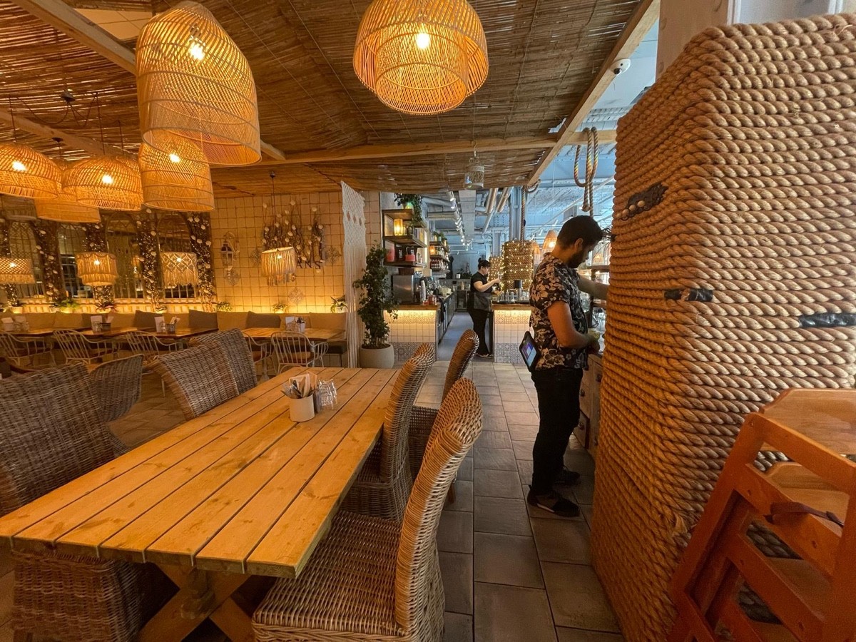From opening facing right. Long table with chairs ahead. Half booth along back left.