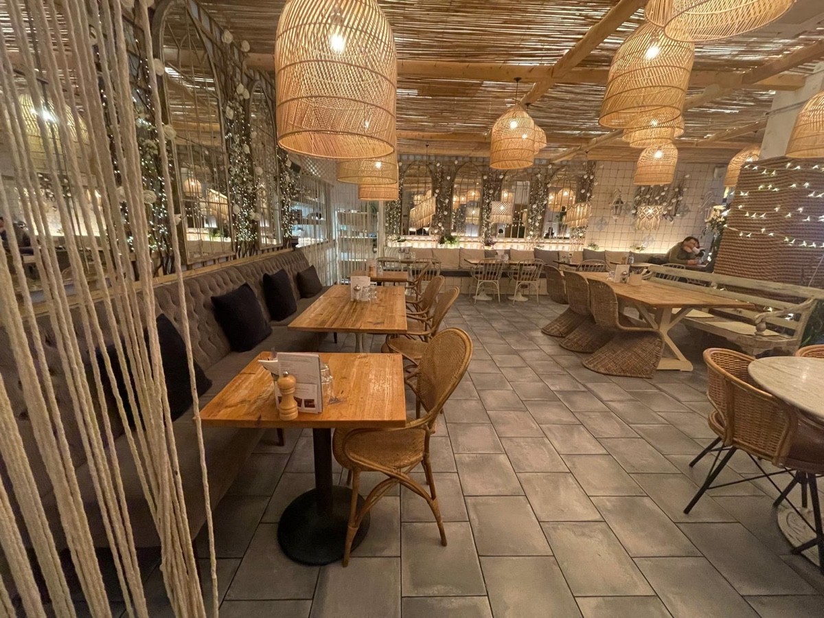 From end of half booth on left facing right. Half booth along left wall. Long table with chairs on back right. Half booth along back wall.
