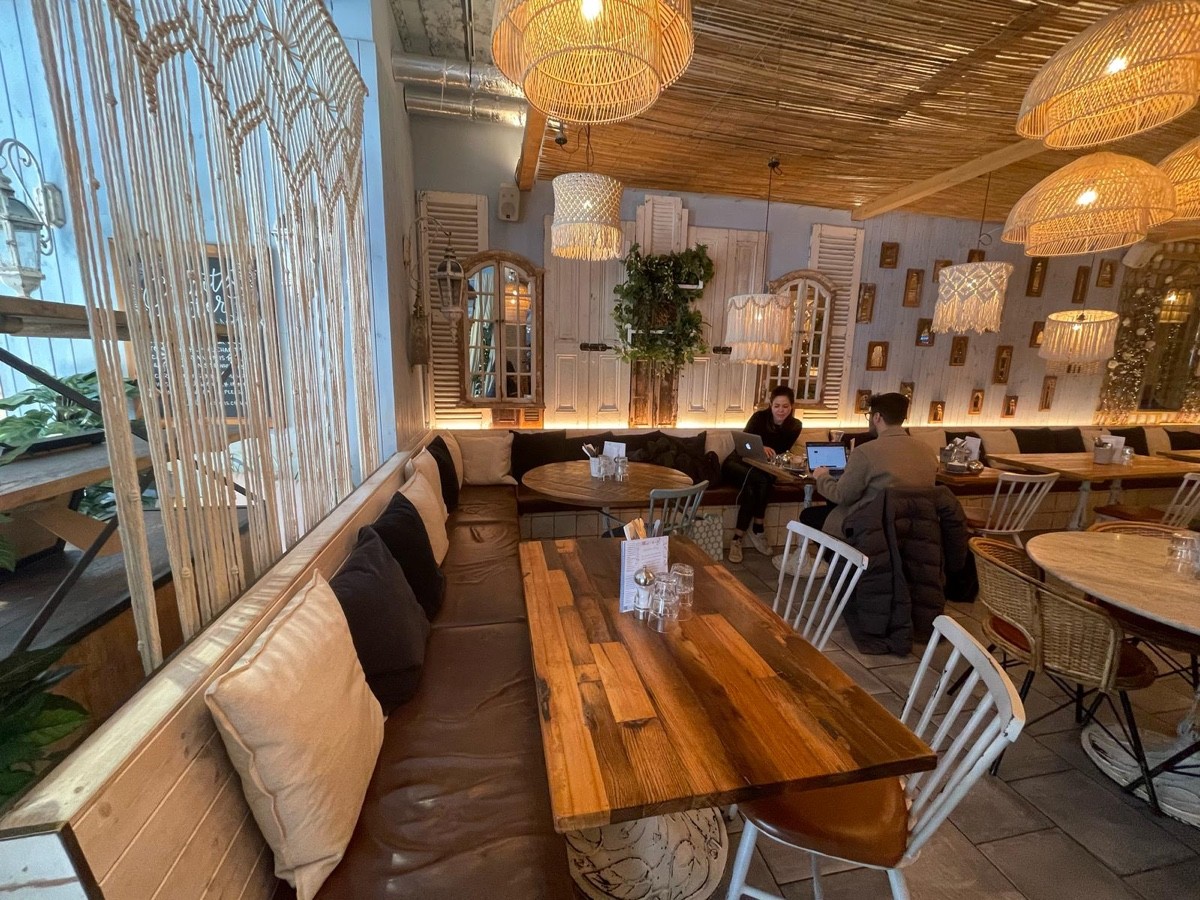 From opening facing left. Half booth along left and back wall with tables and chairs.