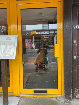 Glass door with yellow frame ahead. Push from yellow handle on right to open.
