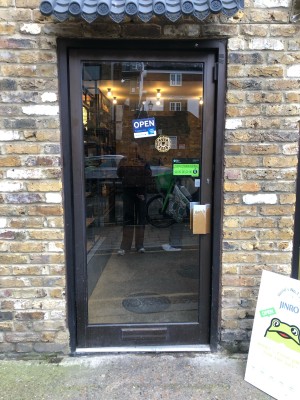 Glass door with black frame. Push metal handle on right to open.