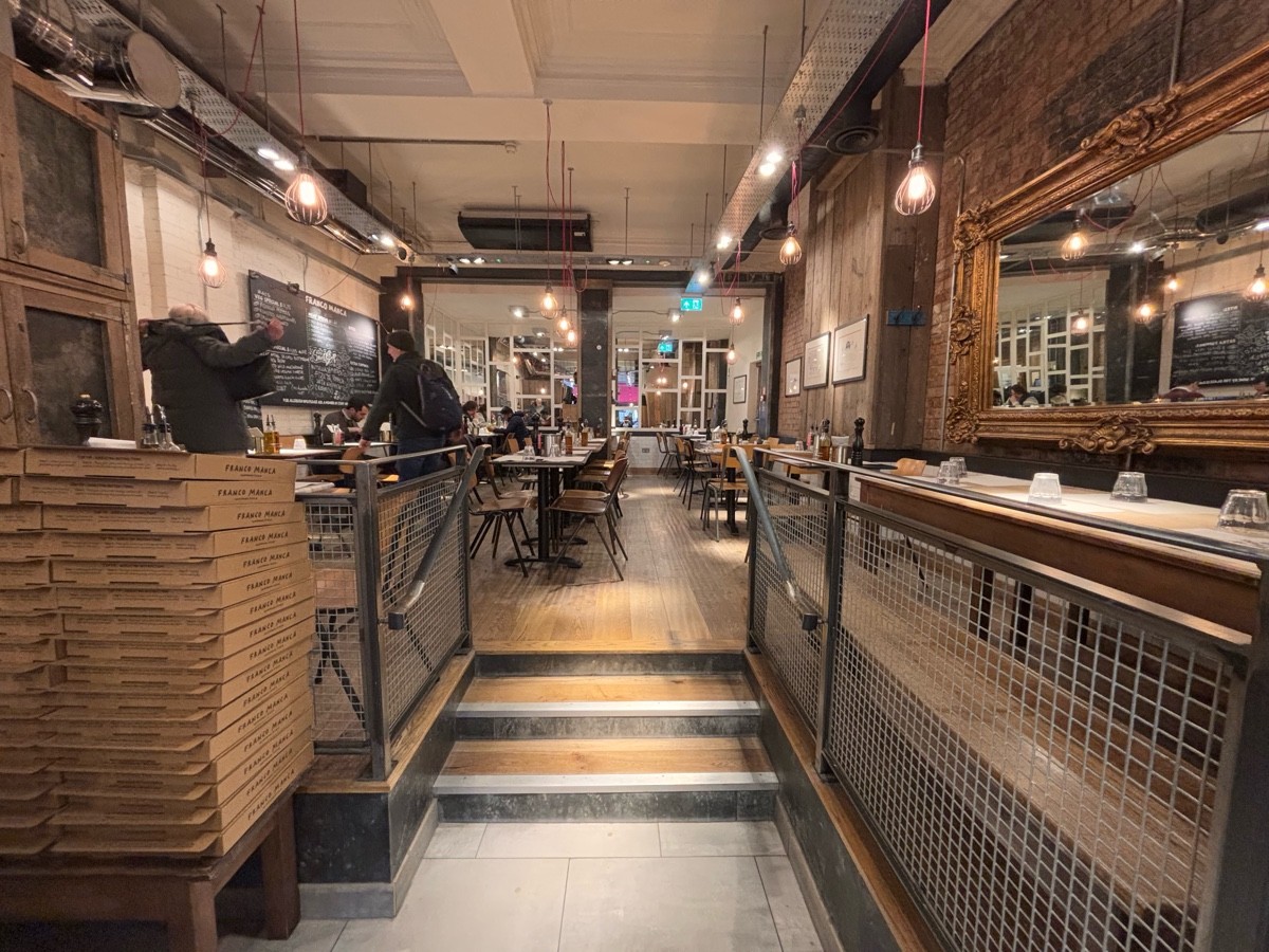 From end of open kitchen facing straight. Stairs going up to more seating ahead. Handrail along left and right.