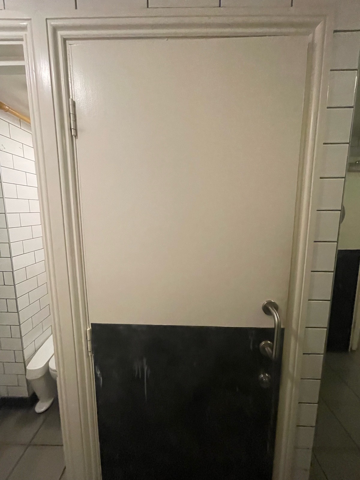Facing white toilet door. Pull sliver handle on right to open.