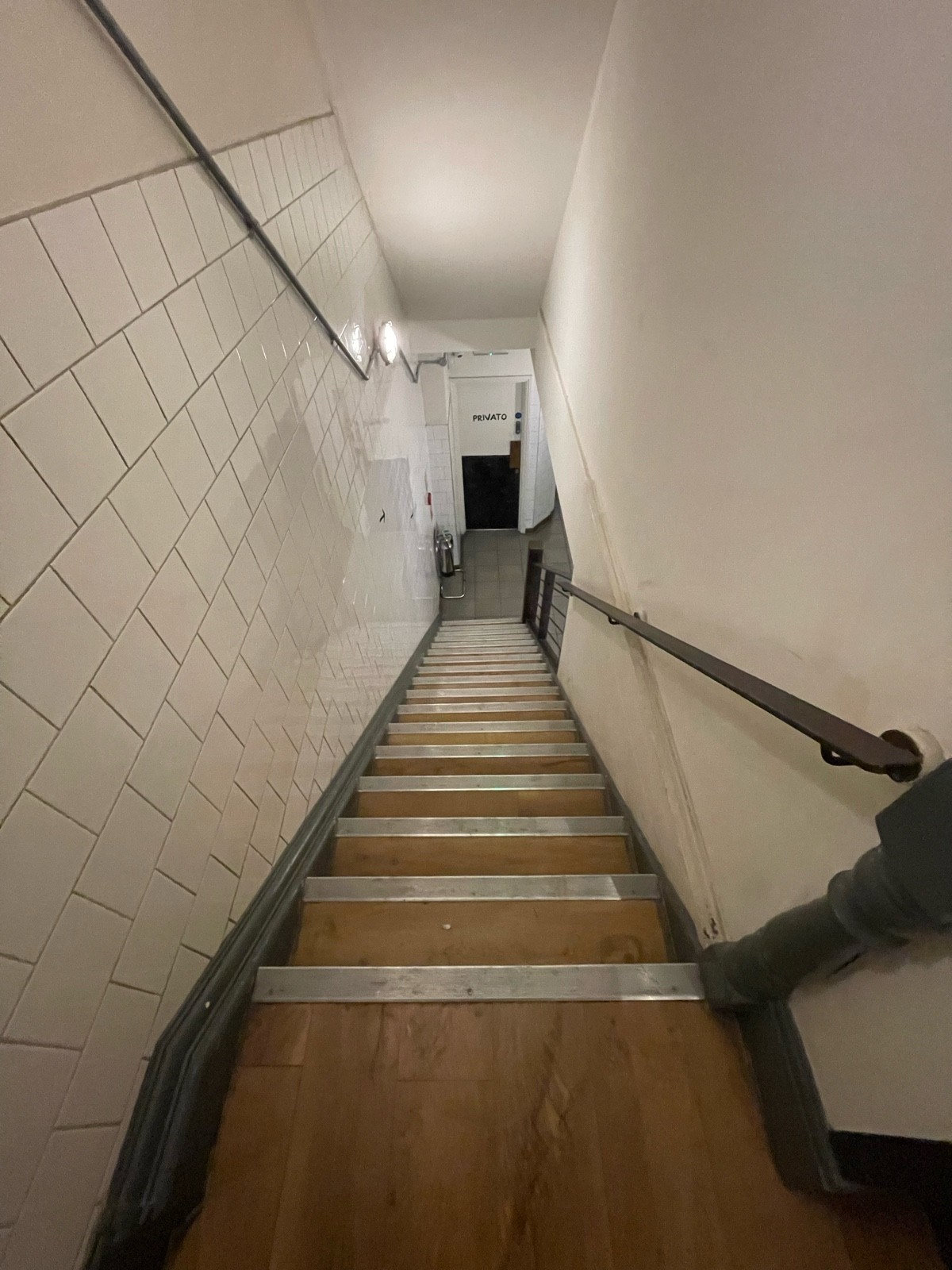 From doorway facing right. Stairs going down ahead. Handrail on right.