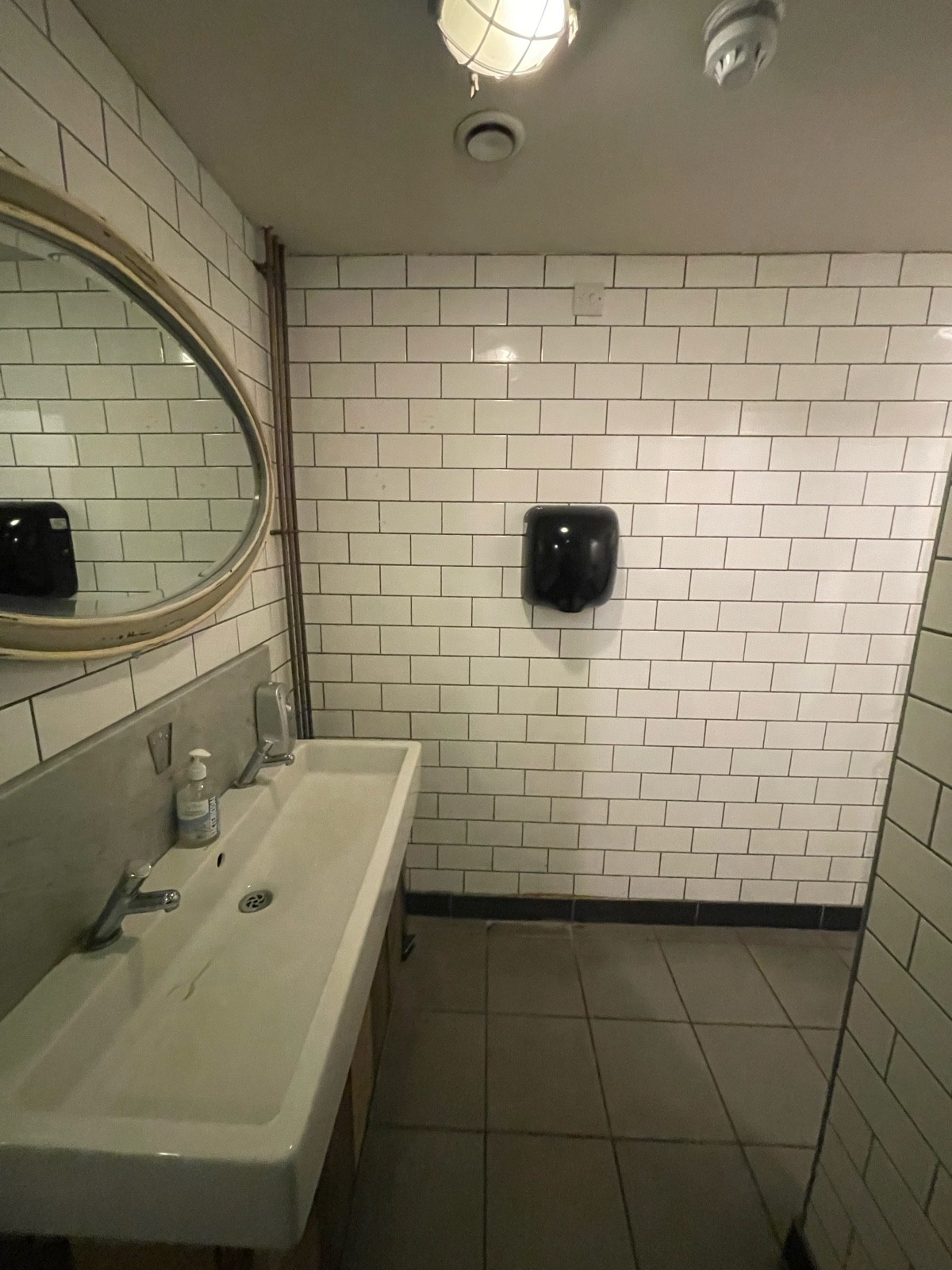 From doorway facing left. Sink on left. Path to toilet cubicles on right.