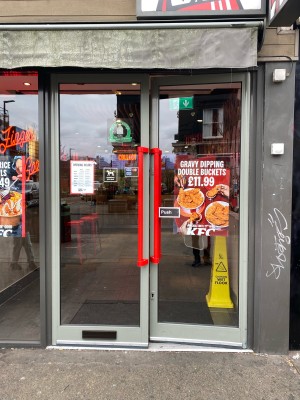 Glass doors with grey frames ahead. Push from red handles in centre to open.