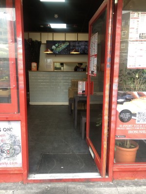 Glass door with red frame. Push handle on left to open.