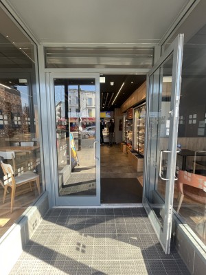 Glass doors with grey frame ahead. Pull silver metal handles in centre to open.
