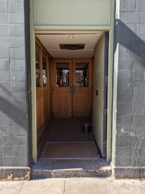 Green door with metal handle on left. Push to open.