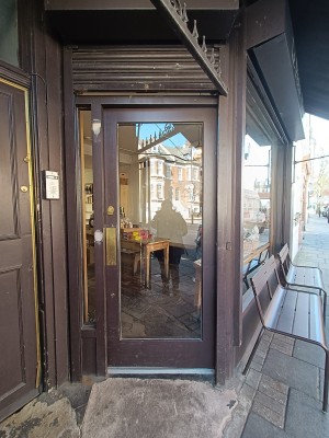 Glass door with brown metal frame. Push from left to open.
