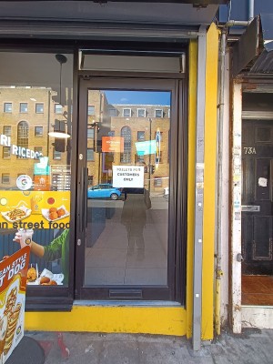Glass door with black, metal frame. Push black handle on left to open.