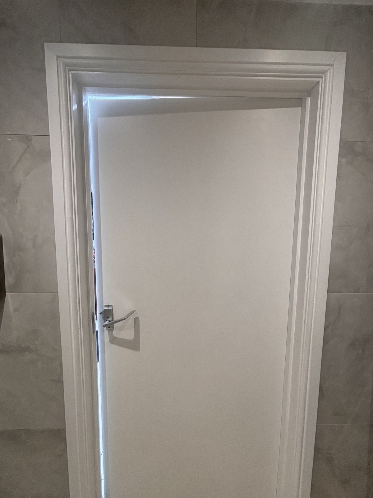 Back of bathroom door. Push metal handle on left to open.