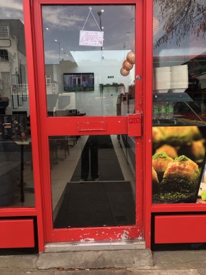 Glass door with red frame. Push handle on right to open.