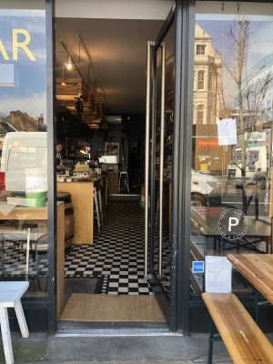 Glass door with black frame. Push handle on left to open.