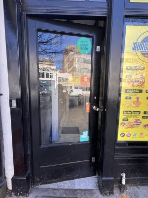Glass doors with black doorframe ahead. Push metal handle at center right to open.