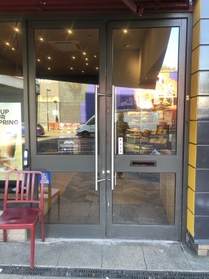 Glass doors with grey frame. Push handle on left to open.
