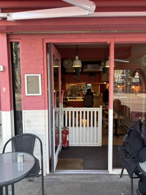 Glass door ahead with pink and white frame. Push to open from handle on right.