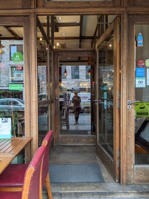 Glass door with wood frame and metal hand on left. Push to open.